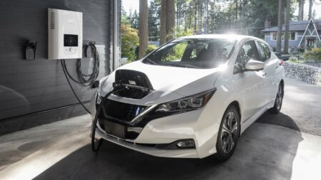 En vit elbil som laddas via en laddbox